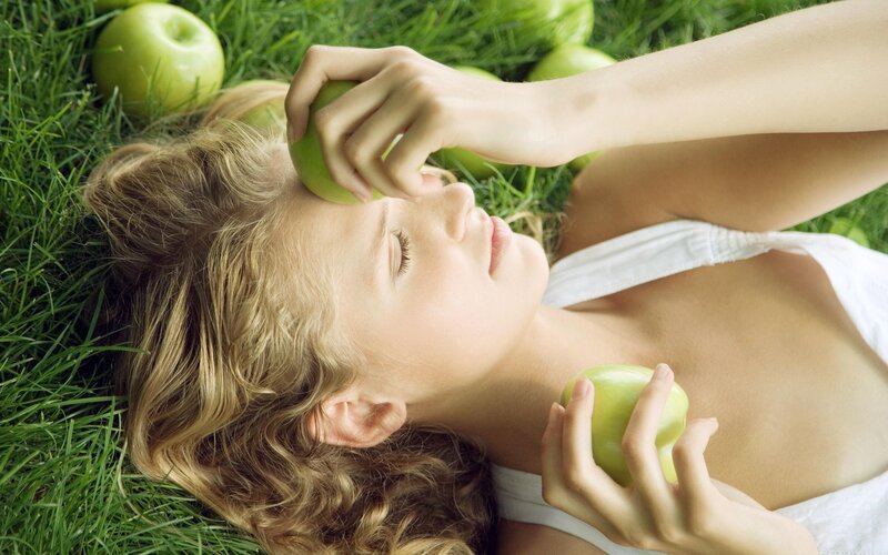 woman lying on grass with apples