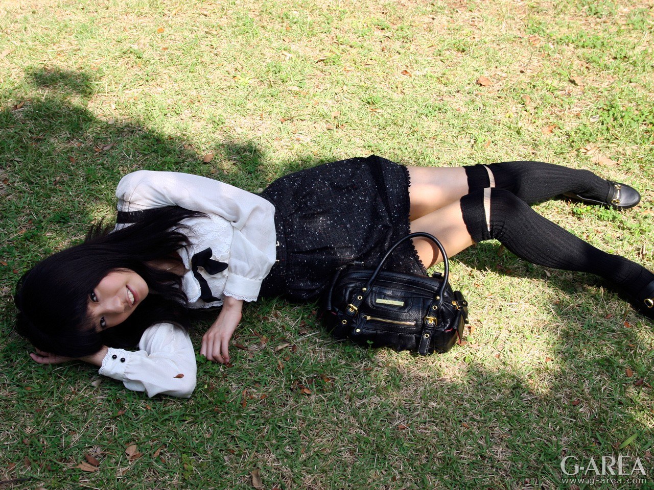 Woman lying on grass with bag