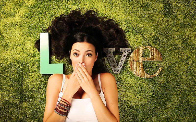 woman lying on grass with love sign