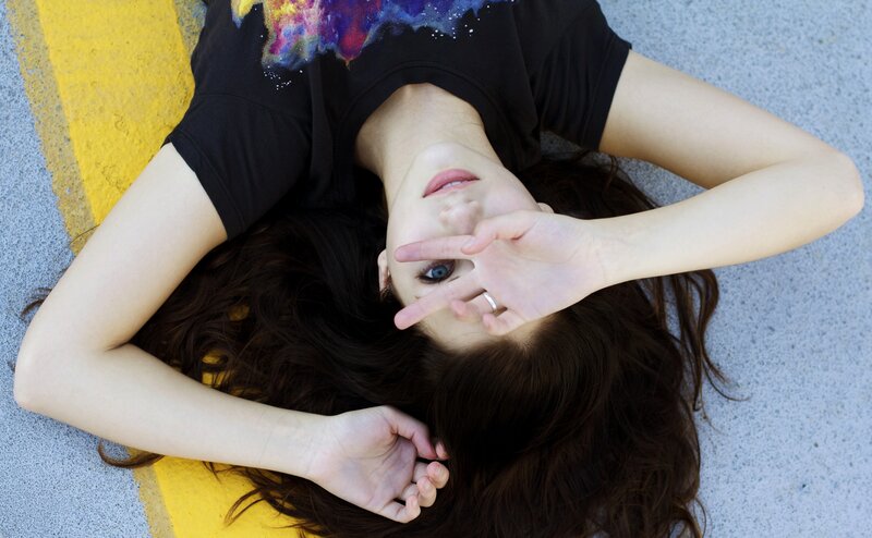 woman lying on ground making peace sign