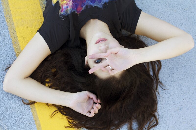 woman lying on ground making peace sign