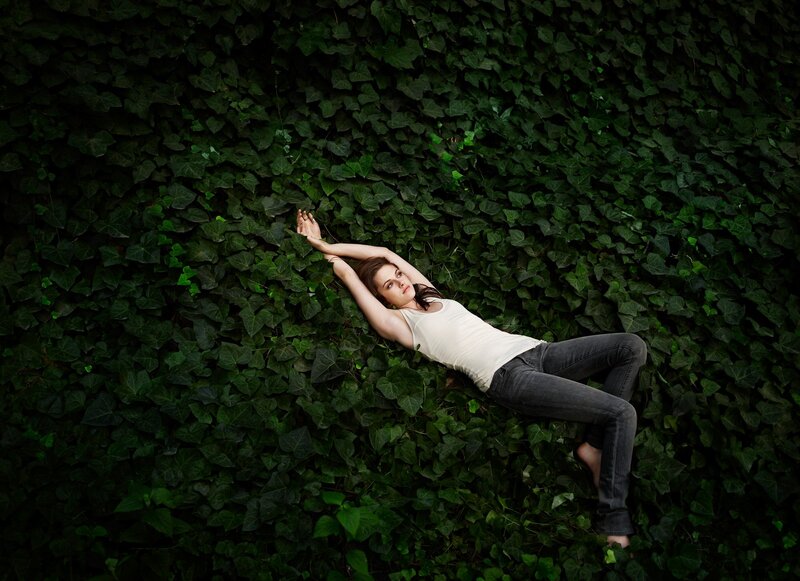 woman lying on ivy wall