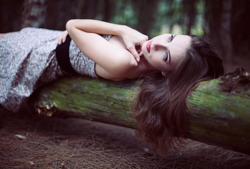 woman lying on log in forest
