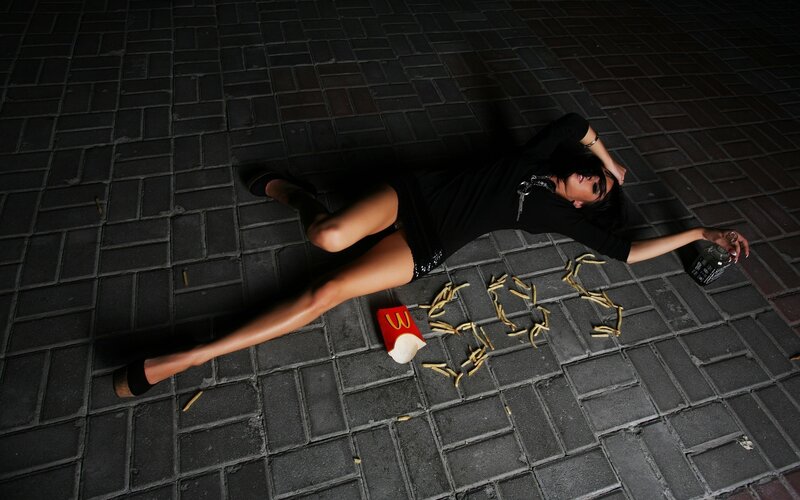 Woman lying on pavement with fast food