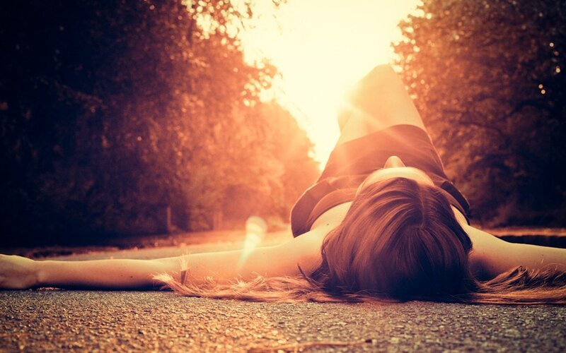woman lying on road at sunset