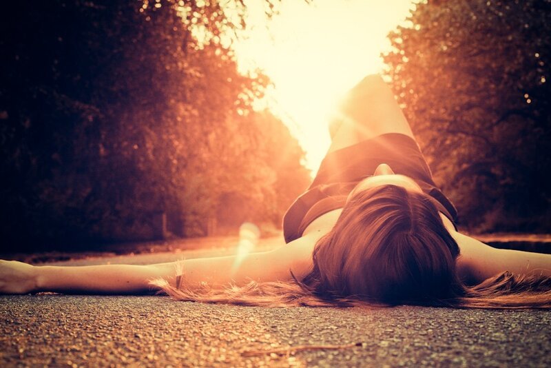 woman lying on road at sunset