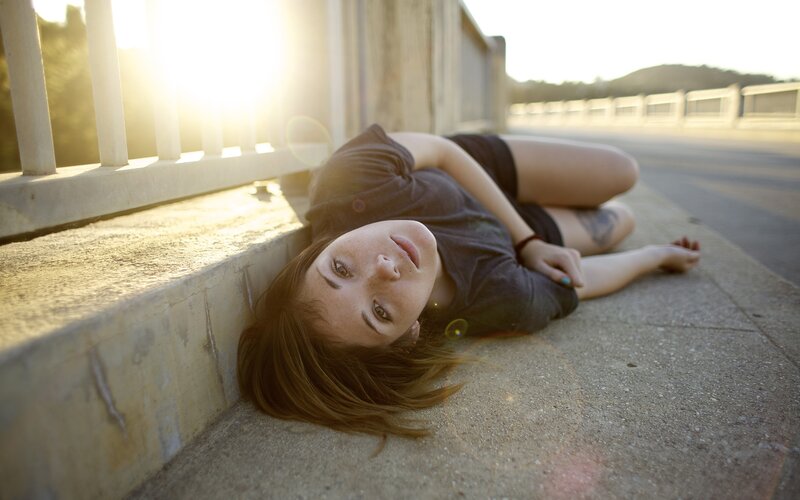 Woman lying on sidewalk at sunset