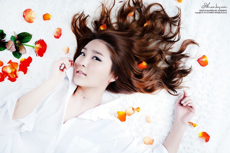 woman lying on white surface with rose petals