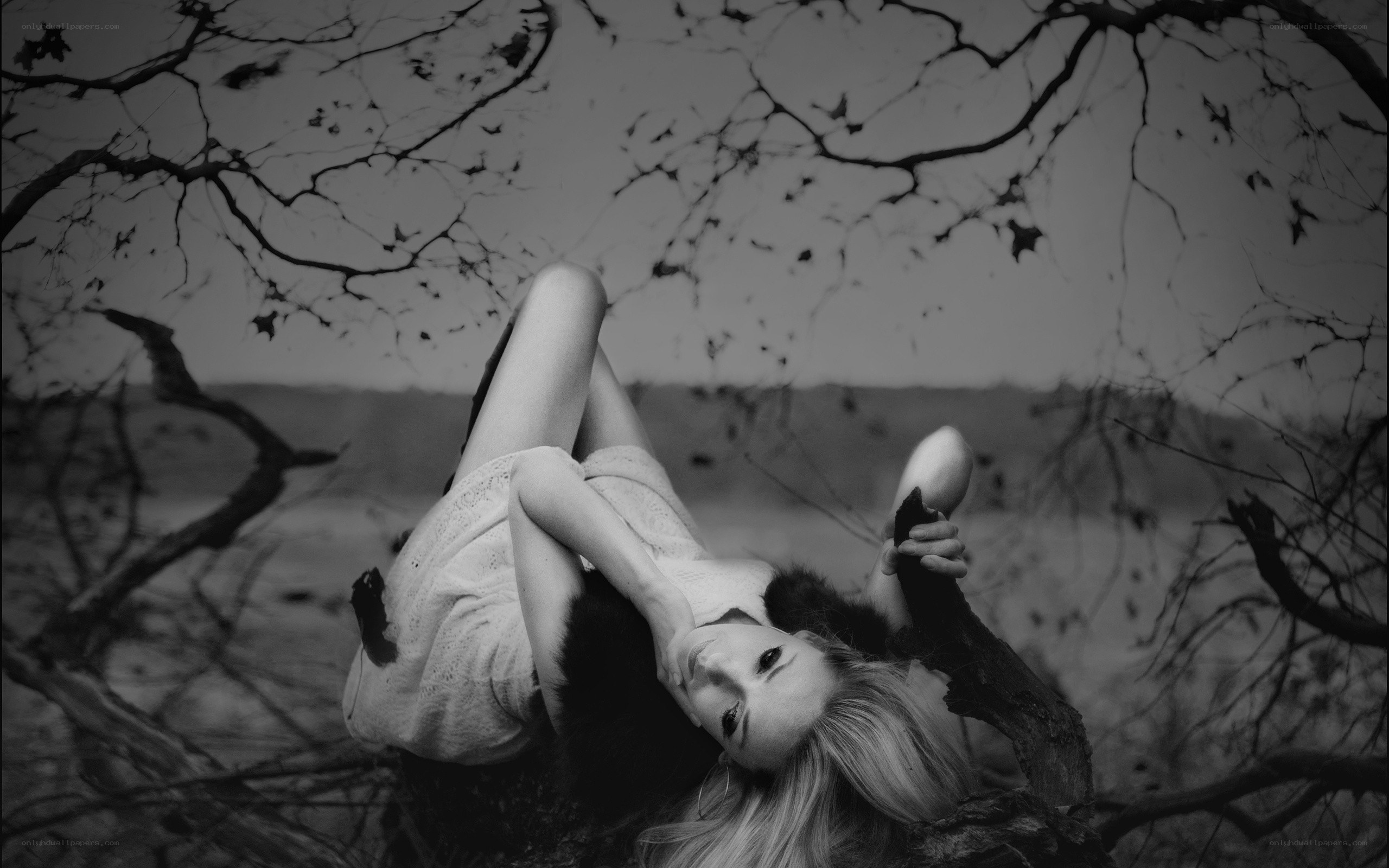woman lying under bare trees