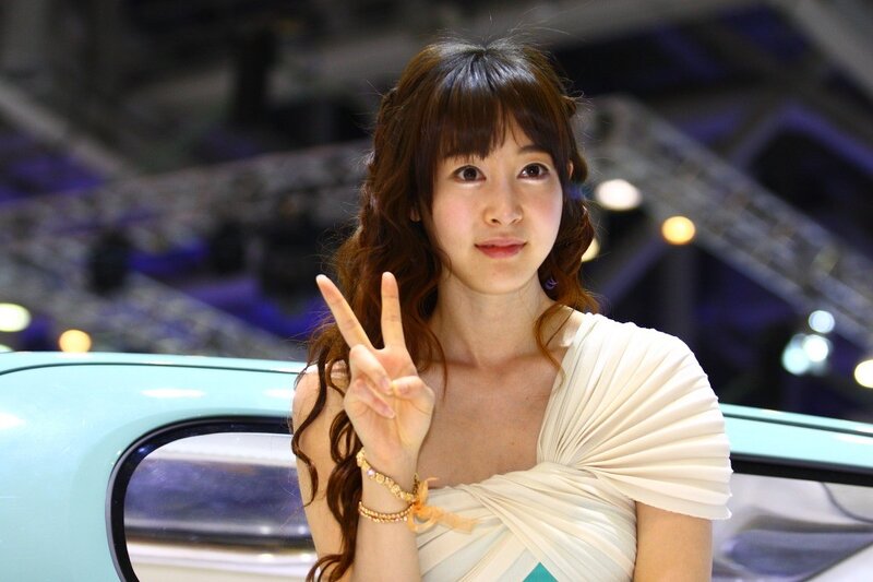 Woman making peace sign at car show