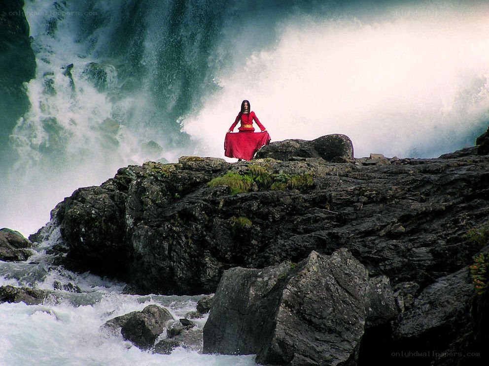 Woman meditating by waterfall