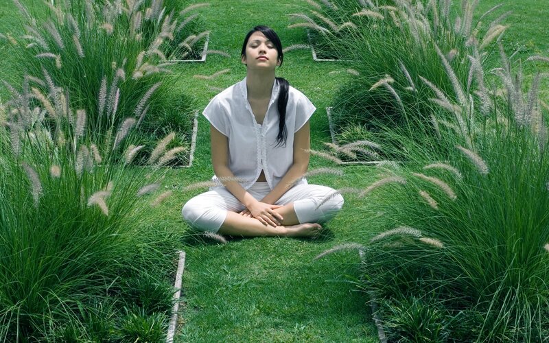 Woman meditating in a grassy field