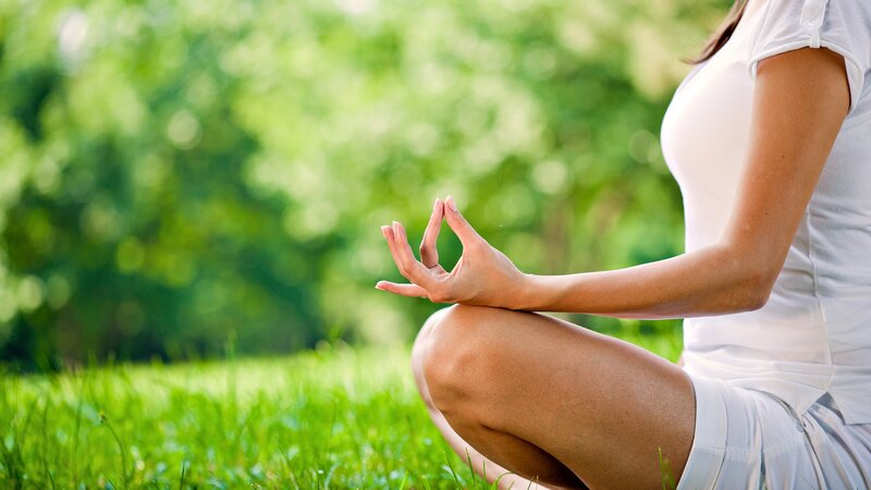 woman meditating on grass