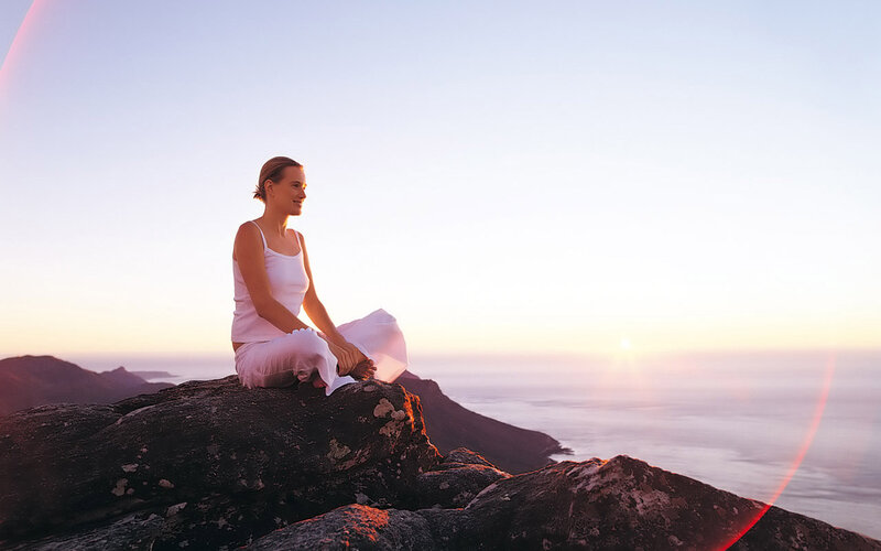 Woman Meditating on Rock