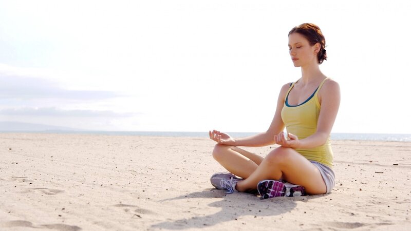 Woman meditating on the beach