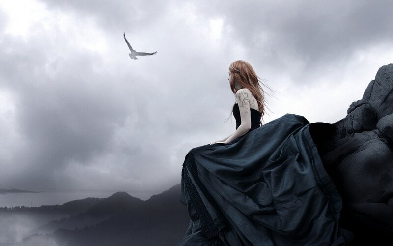 Woman on a cliff with bird