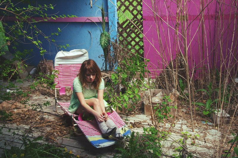 Woman on a deck chair in overgrown yard