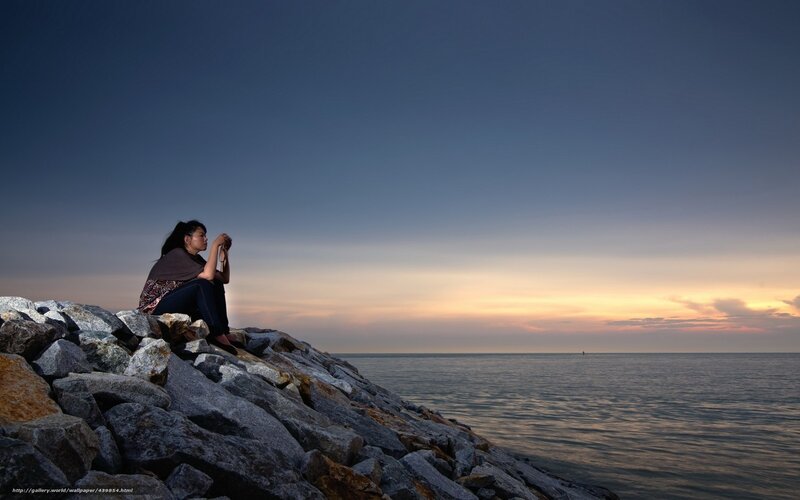 Woman on a rocky shore at sunset