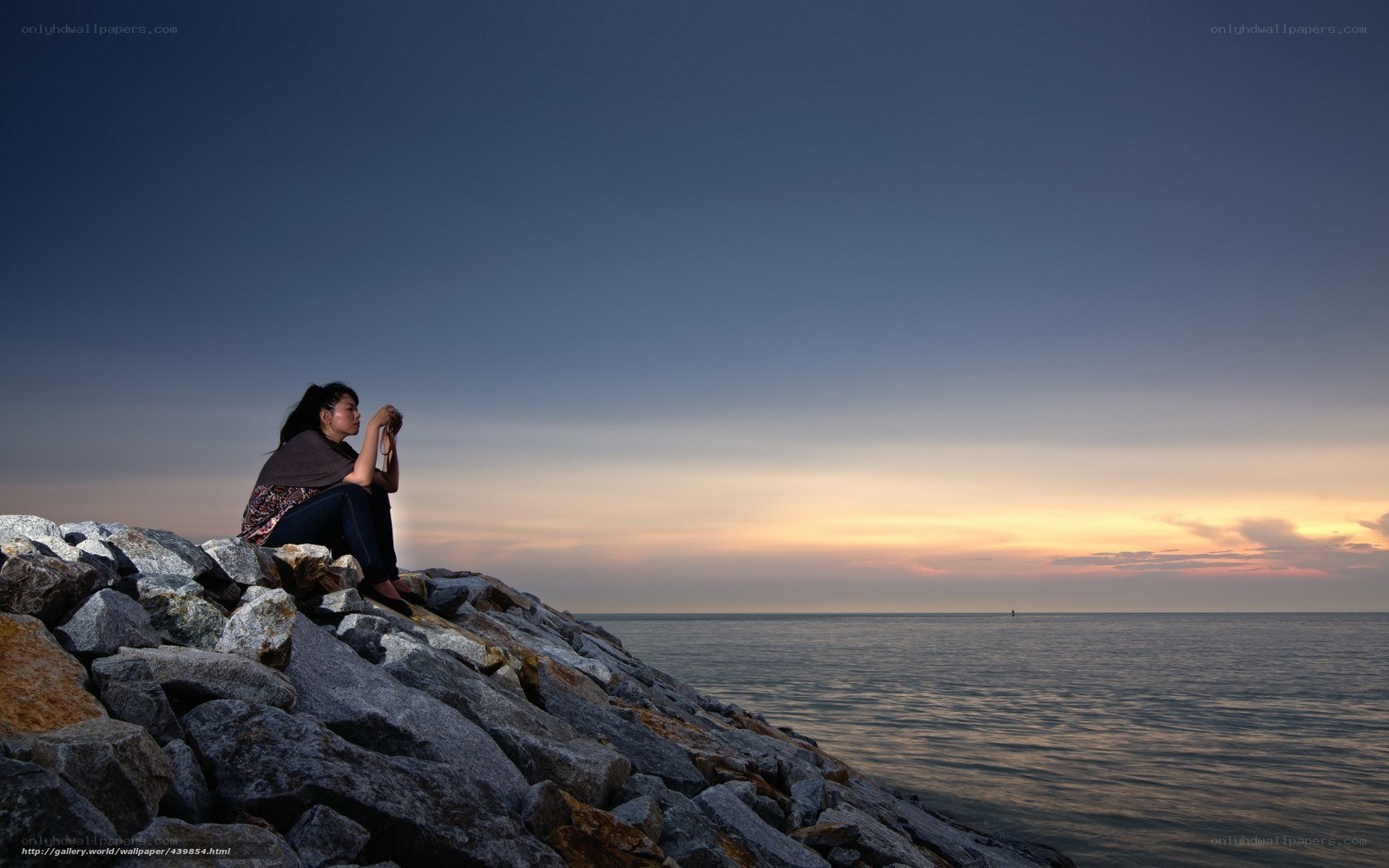 Woman on a rocky shore at sunset