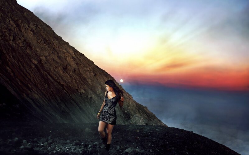 Woman on a volcanic cliff at sunset