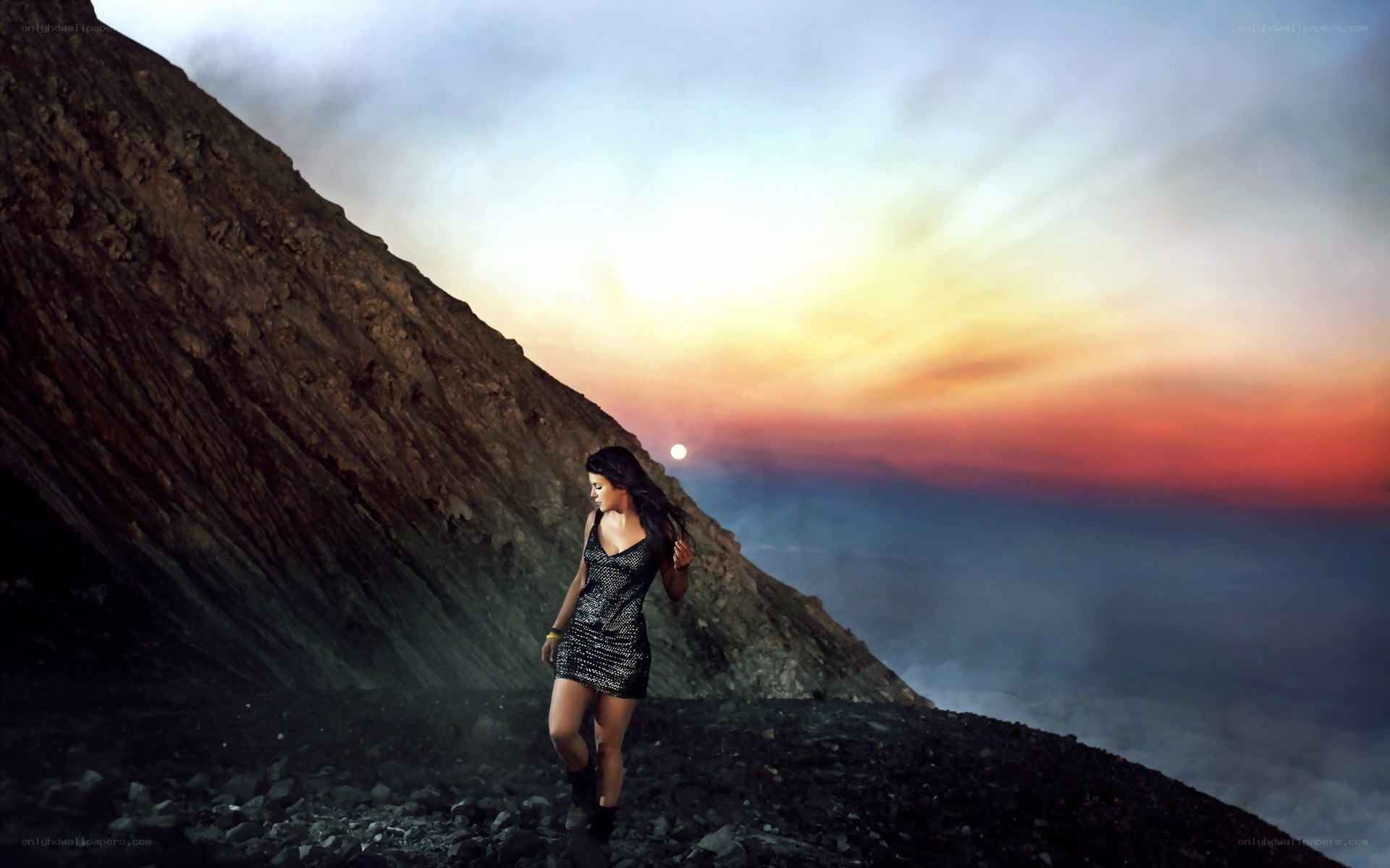 Woman on a volcanic slope at sunset
