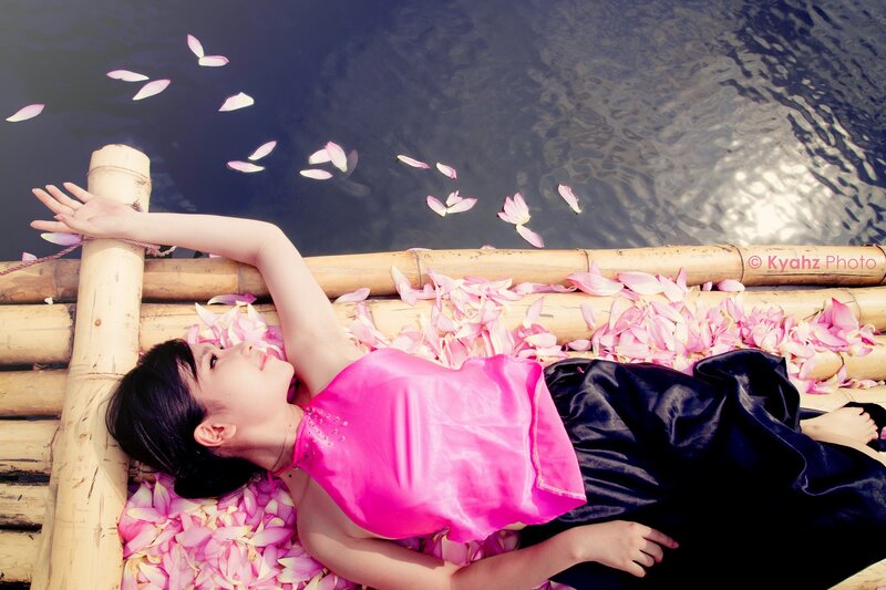 Woman on bamboo raft with petals