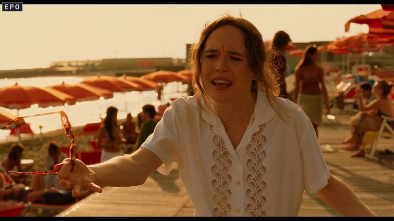 woman on beach holding sunglasses