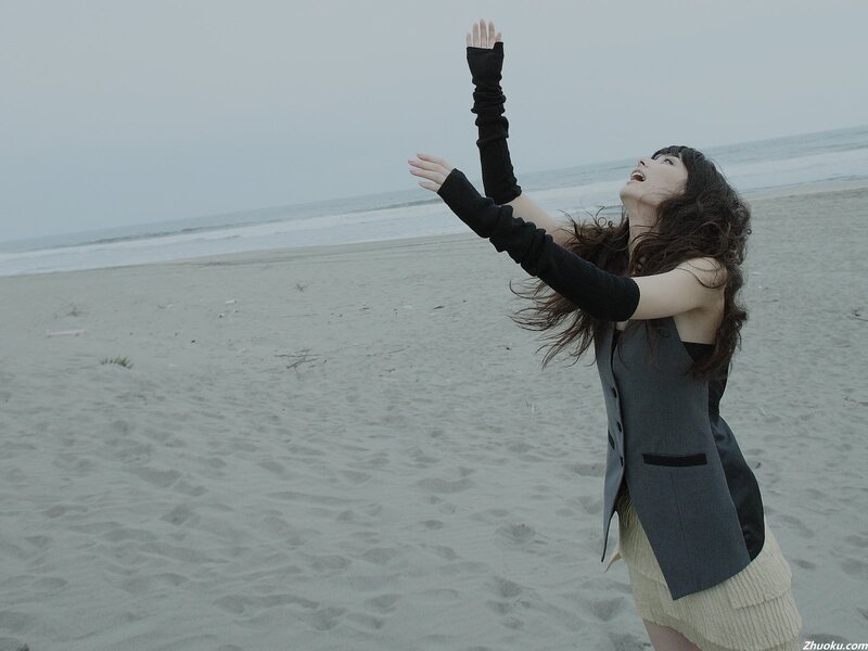 woman on beach with arms raised
