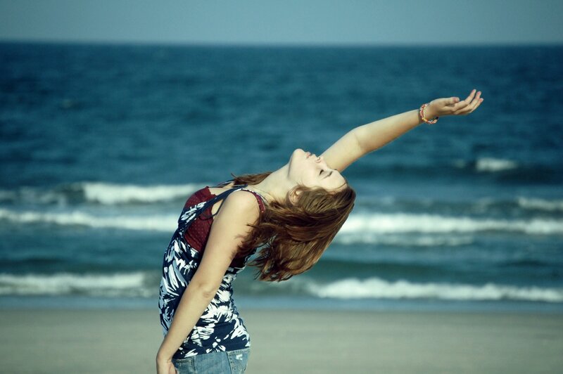 woman on beach with arms raised