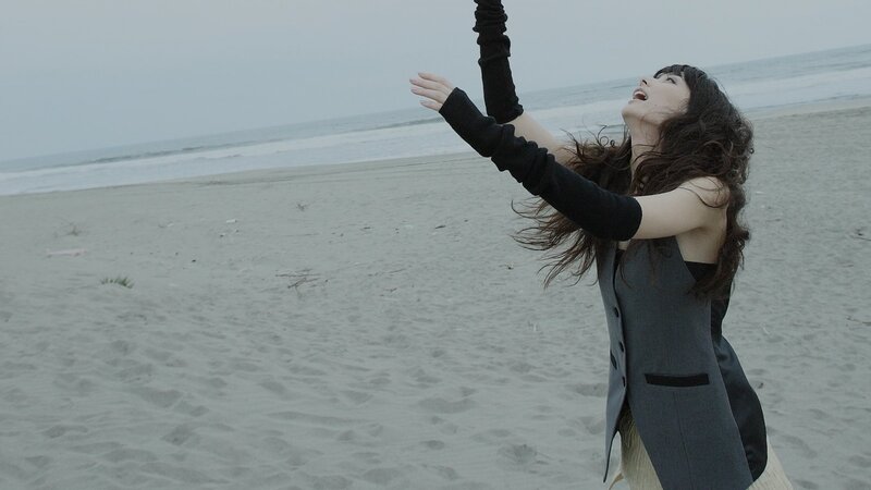 woman on beach with arms raised