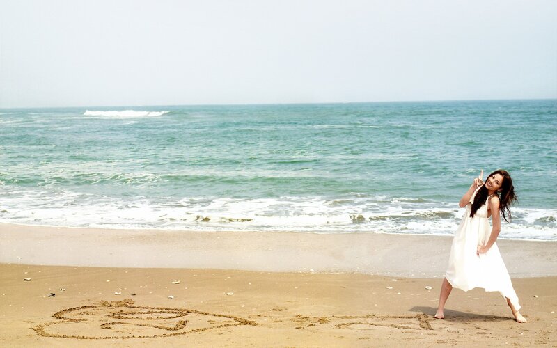 Woman on beach with heart drawing