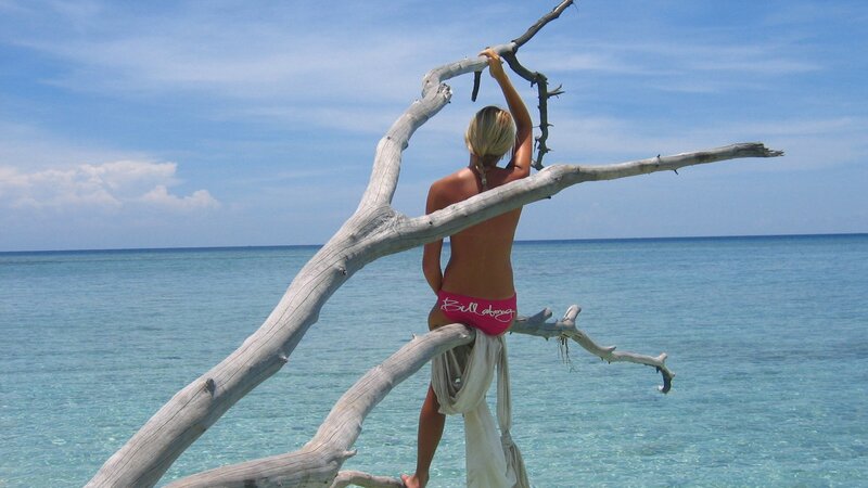 Woman on driftwood at beach