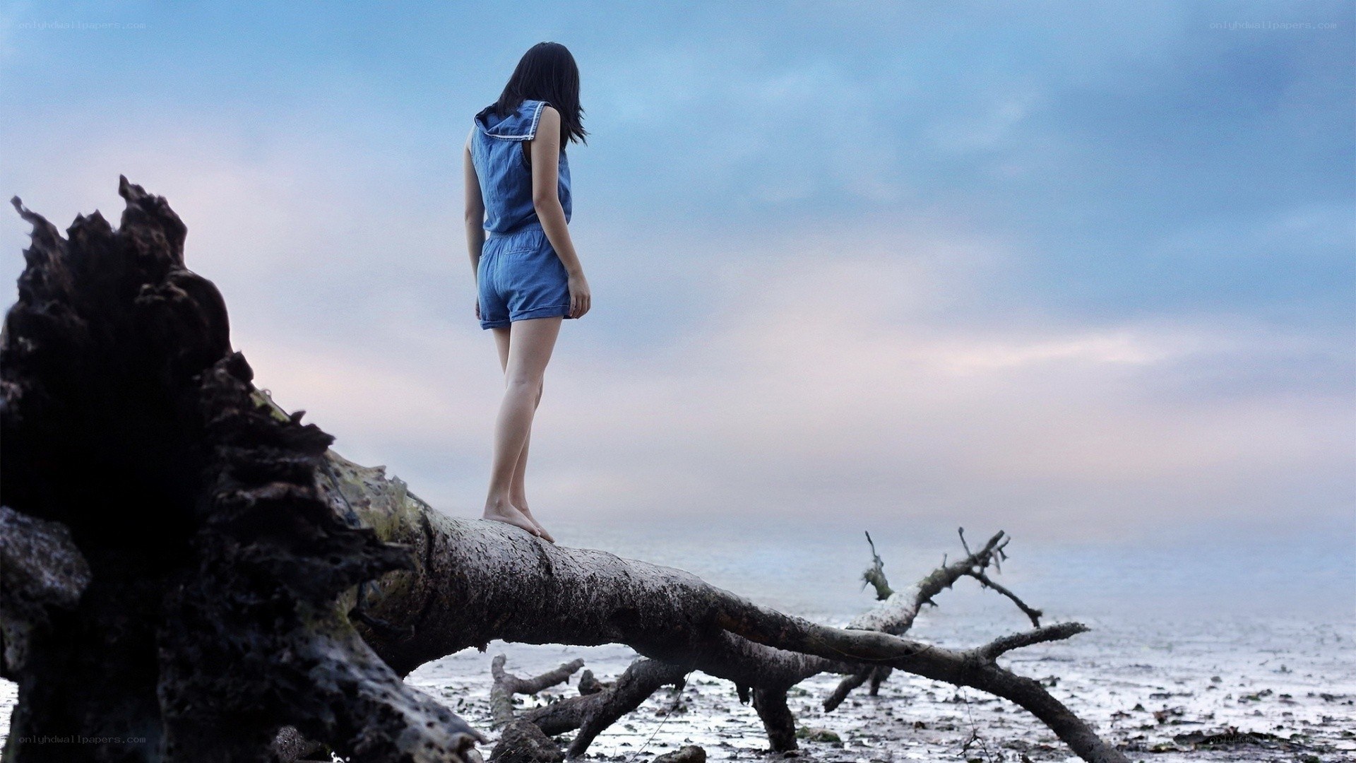 Woman on driftwood at beach