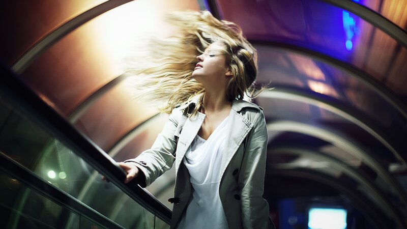 woman on escalator with wind-blown hair