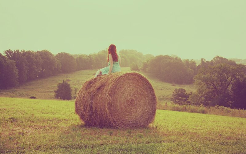 Woman on hay bale in field