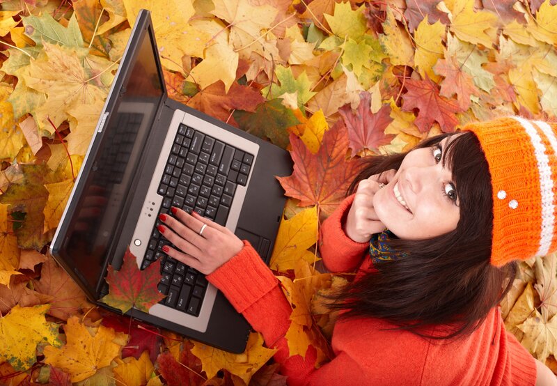 Woman on laptop in autumn leaves