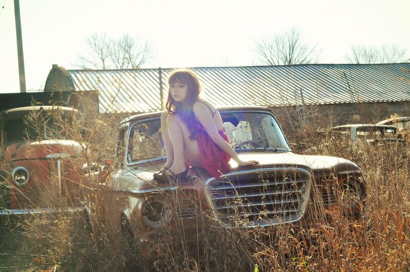 Woman on old car in junkyard