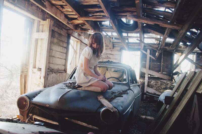 woman on old car in shed