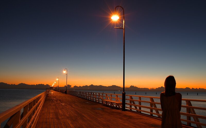 Woman on pier at sunset