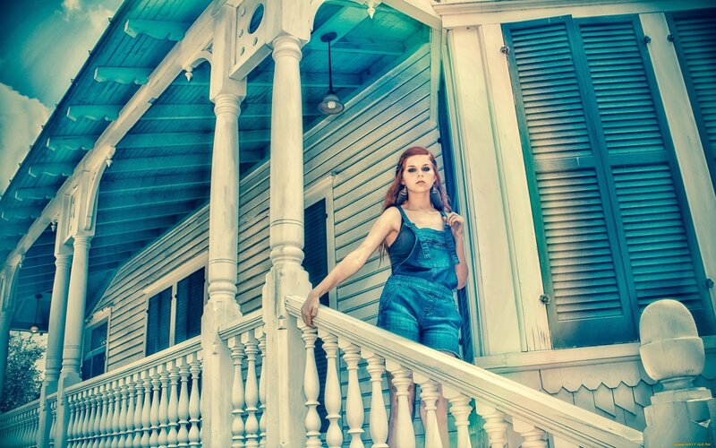 Woman on porch in overalls
