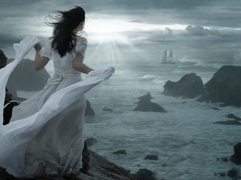 woman on rocky shore watching ship