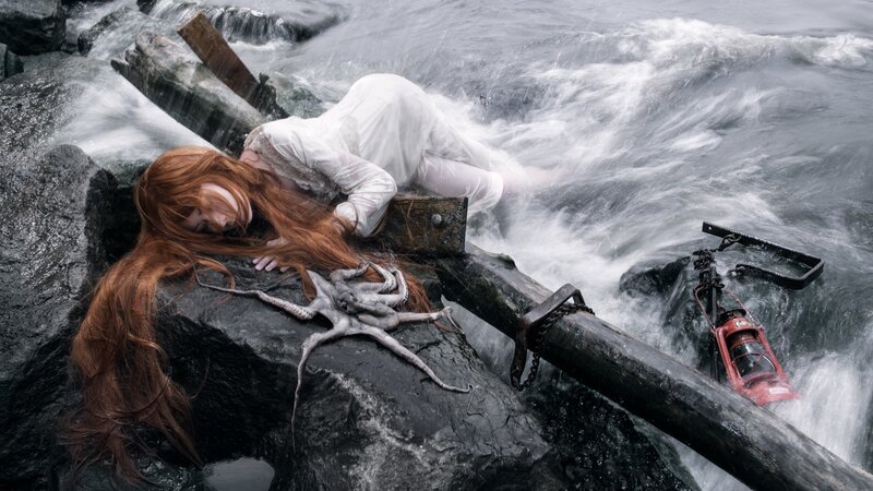 woman on rocky shore with octopus