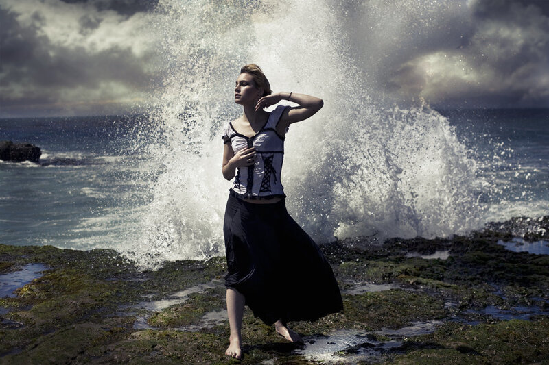 woman on rocky shore with wave