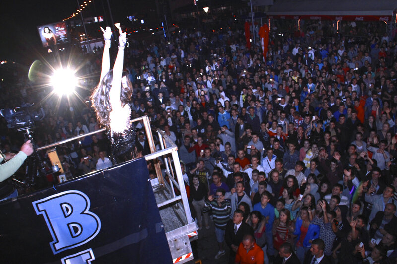 Woman on Stage with Crowd — Black