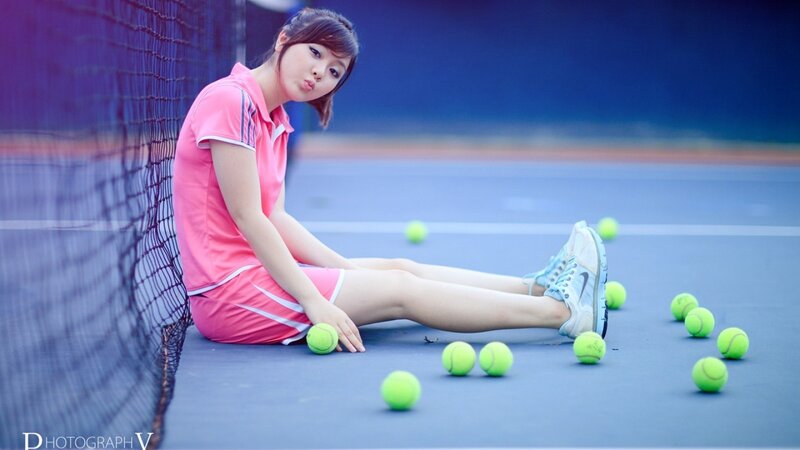 woman on tennis court with balls