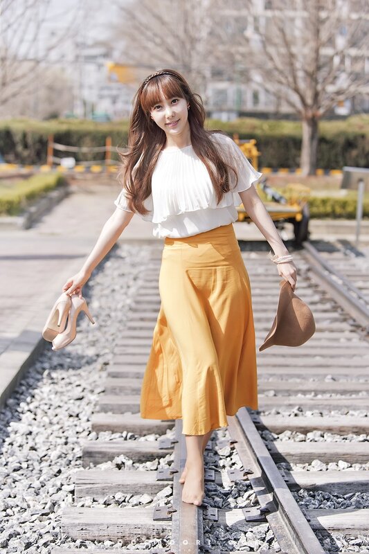 Woman on train tracks holding shoes