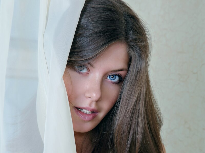 woman peeking from behind curtain