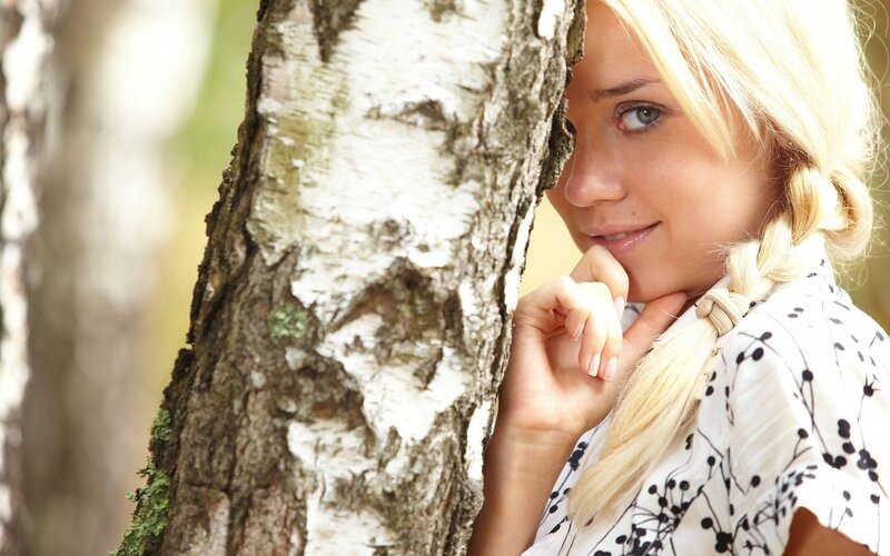 woman peeking from behind tree