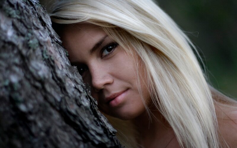 woman peeking from behind tree