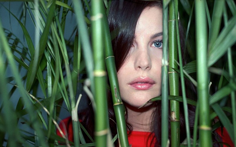 woman peeking through bamboo